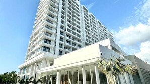 Un moderno hotel de gran altura con una entrada destacada, un área exterior cubierta y un cielo despejado.