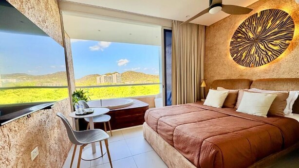 Un dormitorio con una cama grande, un escritorio, una silla y vistas al exterior.