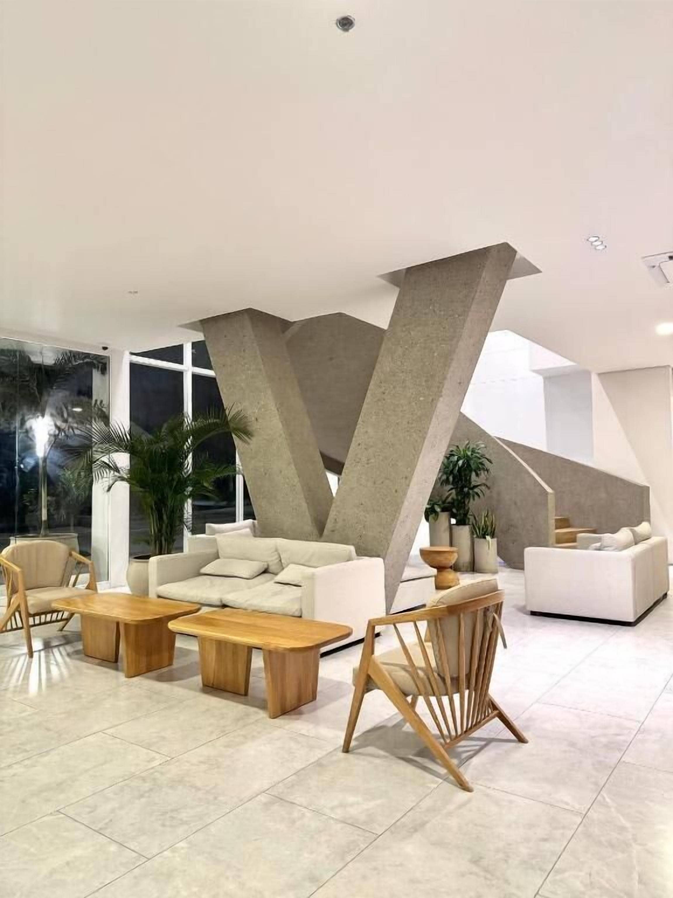 A modern living room with a large sofa, wooden coffee tables, and a unique concrete structure.