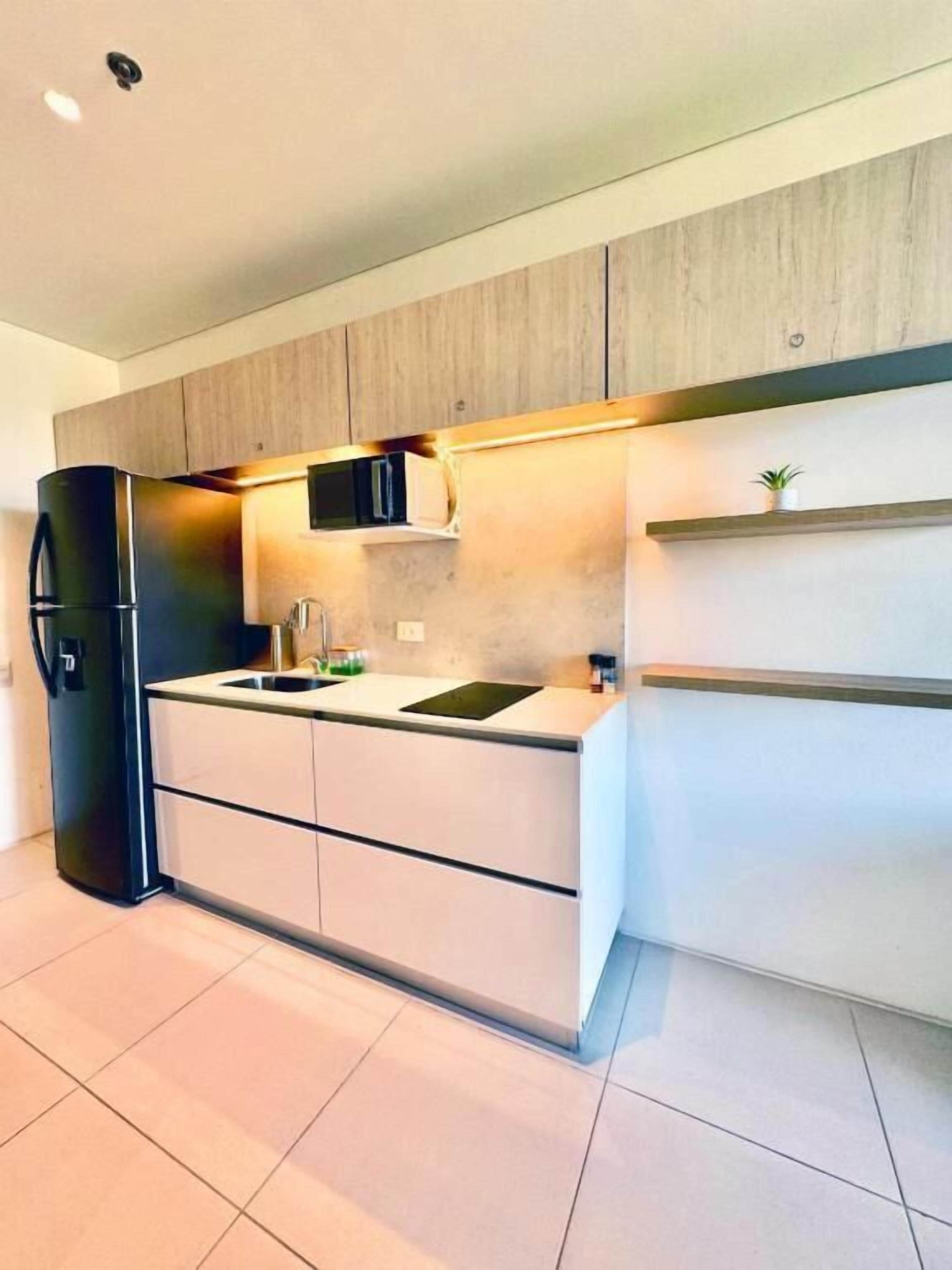 Una cocina moderna con refrigerador empotrado, un lavamanos y armarios de madera.