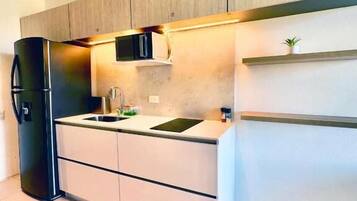 Una cocina moderna con refrigerador empotrado, un lavamanos y armarios de madera.
