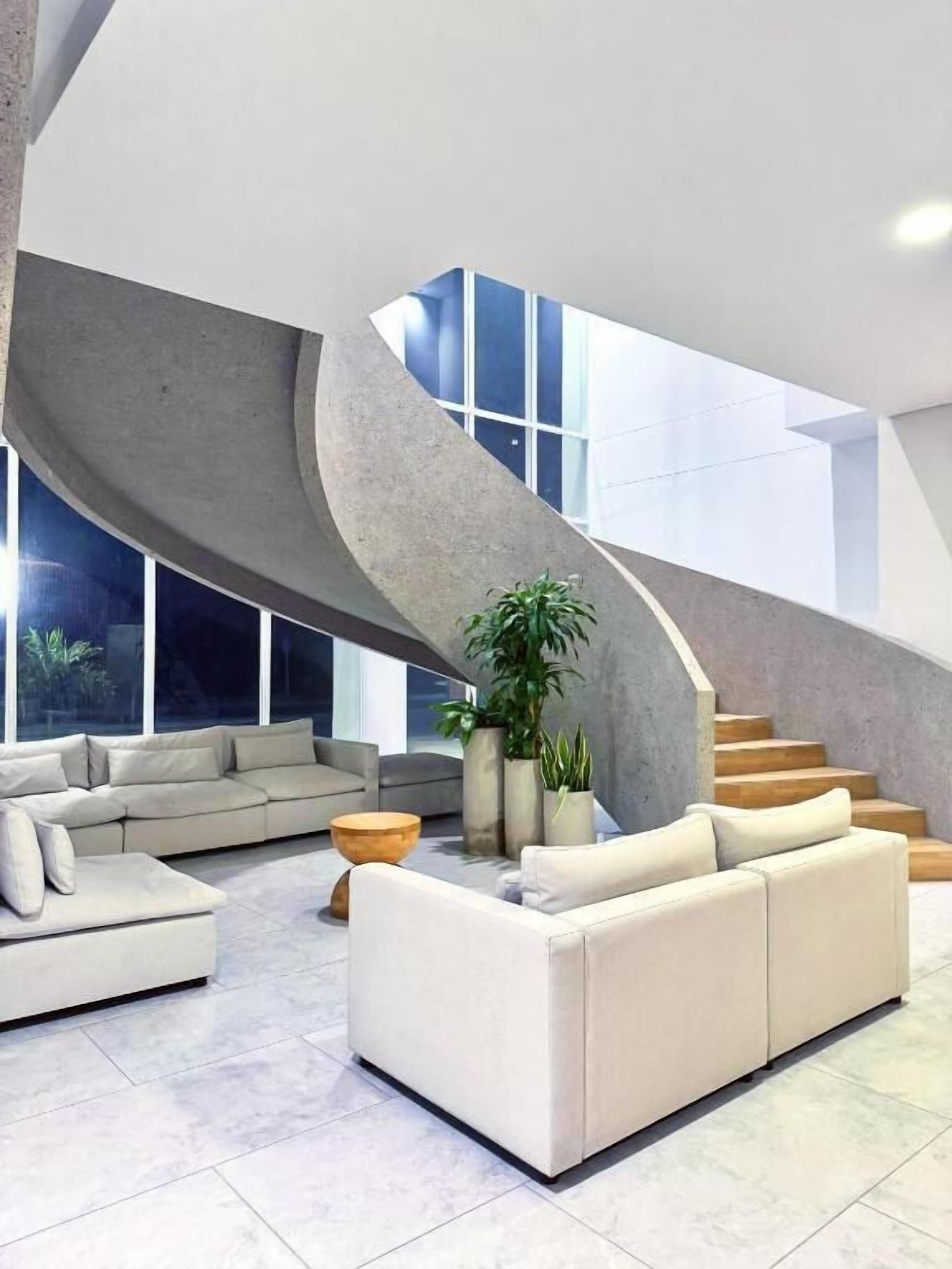 Un interior moderno con una escalera curva, un sofá y una mesa de centro.