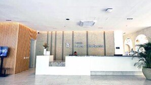 A hotel reception area with a modern design, a reception desk, and a large potted plant. - Suite Vista A Reserva y Mar Piso Alto En Bello Horizonte (Santa Marta)