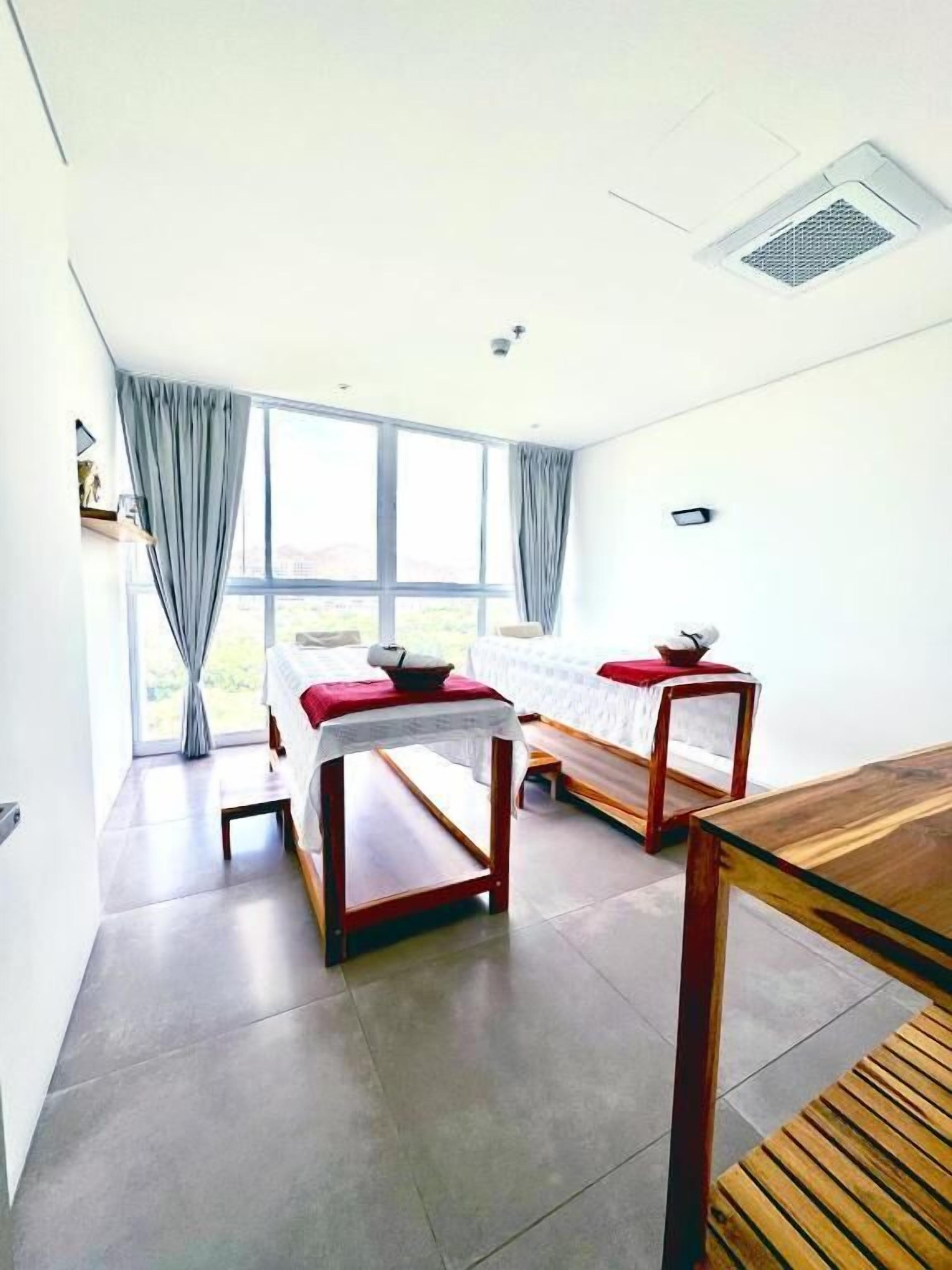 Una habitación moderna con una cama, una mesa de madera y un ventanal con cortinas.