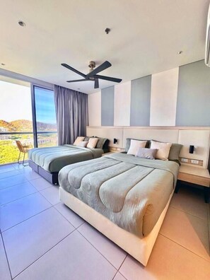Um quarto moderno com uma cama grande, um ventilador de teto e vista para o exterior.
