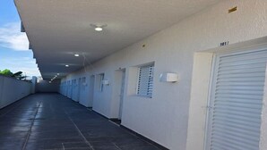 Un pasillo con piso de baldosas, paredes blancas y puertas cerradas.