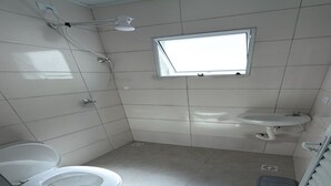 Un baño pequeño y limpio con inodoro, lavabo y ducha.
