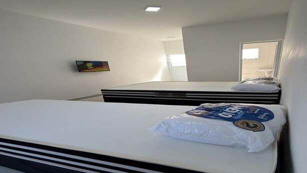 Una habitación con cama, ventana y televisor montado en la pared.