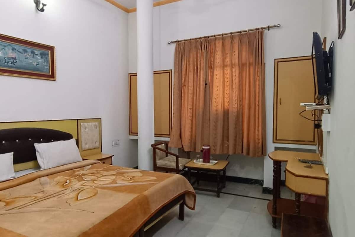 Une chambre d’hôtel équipée d’un lit, d’un bureau, d’une chaise, d’une télévision et d’une fenêtre avec des rideaux.