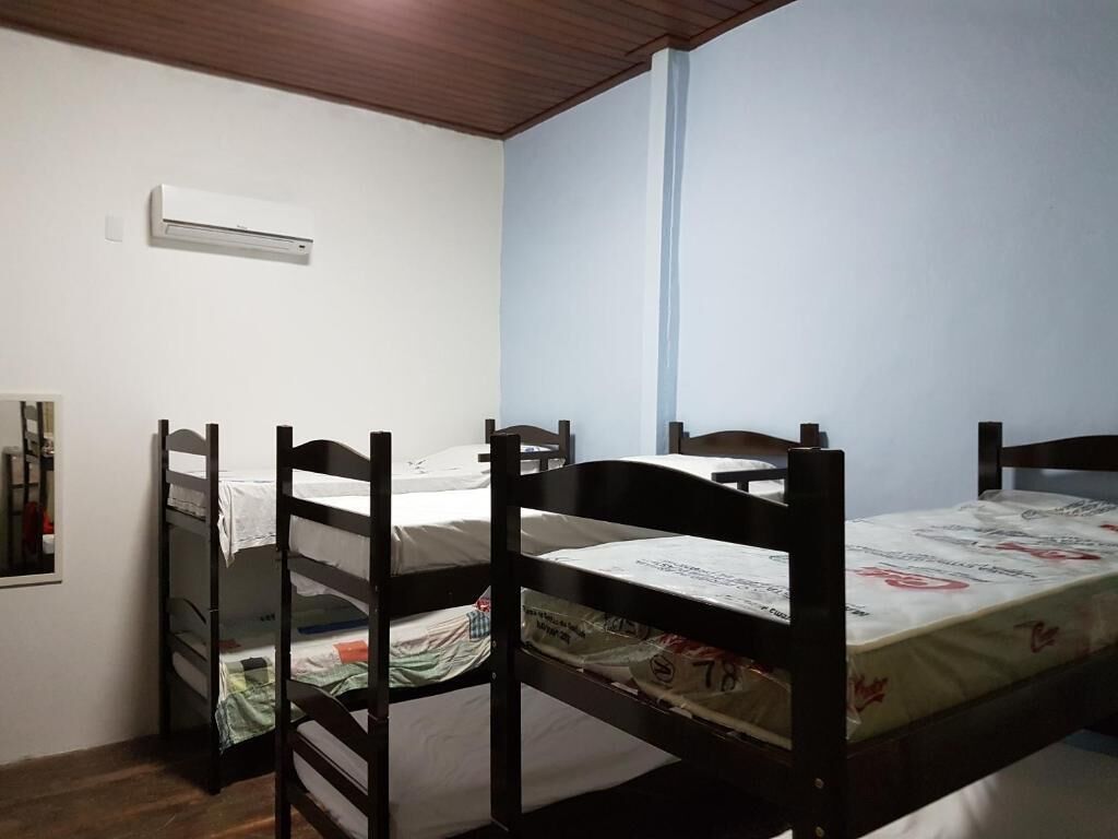 A room with bunk beds, a wall-mounted air conditioner, and a window with a blue blind.