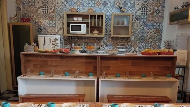 A kitchen with patterned tiles, a microwave, and a buffet setup. - Hostel Casa de Avany (Cachoeira)
