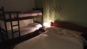 A room with bunk beds, a single bed, a nightstand, and a wall-mounted lamp. - Hostel Casa de Avany (Cachoeira)