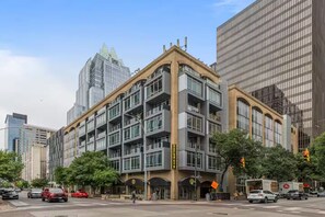 A multi-story building with a modern architectural style, featuring a prominent corner entrance and large windows. - Great 2x1 Loft Apartment in Downtown Austin (Austin)