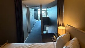 Ein Hotelzimmer mit Bett, Lampe und Blick auf den Flur und ein weiteres Zimmer.