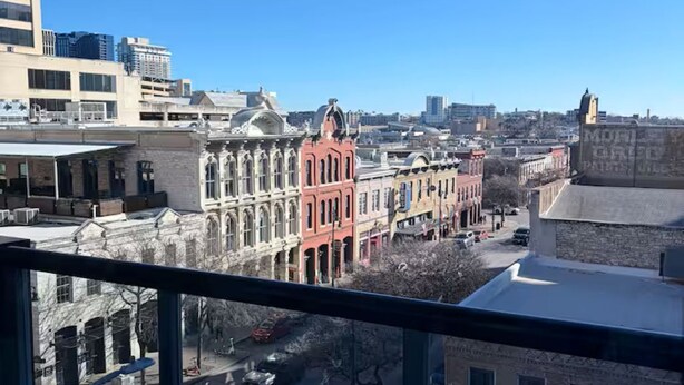 Stadtansicht mit historischen Gebäuden, blauem Himmel und Blick von einem Balkon.