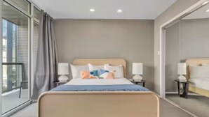 Una camera d'albergo con un letto grande, due comodini con lampade, una finestra con tende e vista sull'esterno.