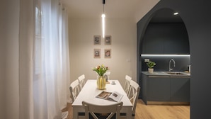Une cuisine moderne dotée d’un îlot central intégré, de meubles blancs et d’un luminaire suspendu.