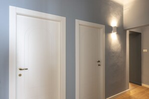 A hallway with two white doors, one with a visible lock, and a wall-mounted light fixture. - Apartments Florence - San Marco Design Apartment (Firenze)