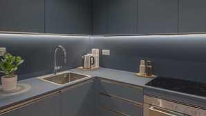 Une cuisine moderne avec un plan de travail bleu foncé, un évier en acier inoxydable et un four encastré.