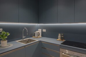 Eine moderne Küche mit dunkelblauer Arbeitsplatte, Edelstahl-Spüle und integriertem Backofen.