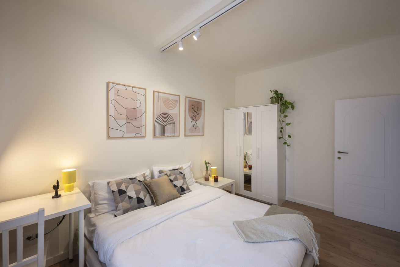 Une chambre à coucher comprenant un lit, des tables de chevet, une armoire et des œuvres d’art murales.