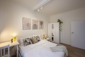 Ein Schlafzimmer mit Bett, Nachttischen, einem Kleiderschrank und Wandbildern.
