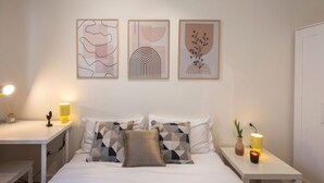 Une chambre à coucher bien rangée, avec un lit, des tables de chevet et des œuvres d’art accrochées au mur.
