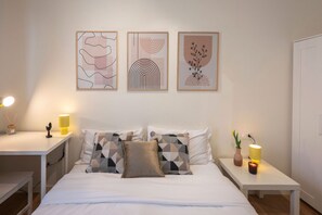 Ein ordentlich eingerichtetes Schlafzimmer mit einem Bett, Nachttischen und Wandbildern.