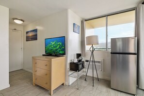 Eine moderne Küche mit Kühlschrank, Mikrowelle, Kaffeemaschine und Fernseher auf einem Holzkabinett.