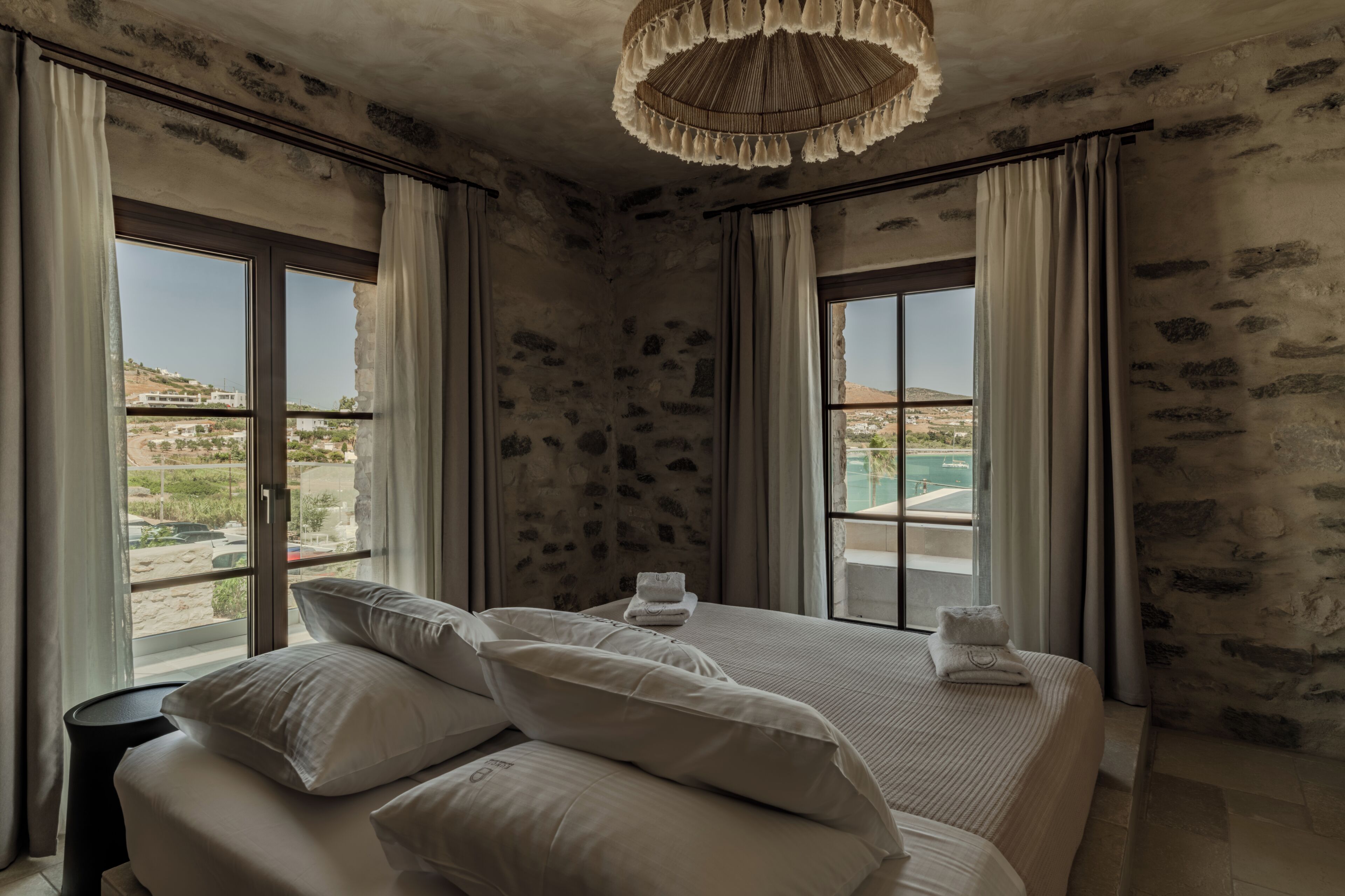 Un dormitorio con una cama grande, dos ventanas y vistas al paisaje.