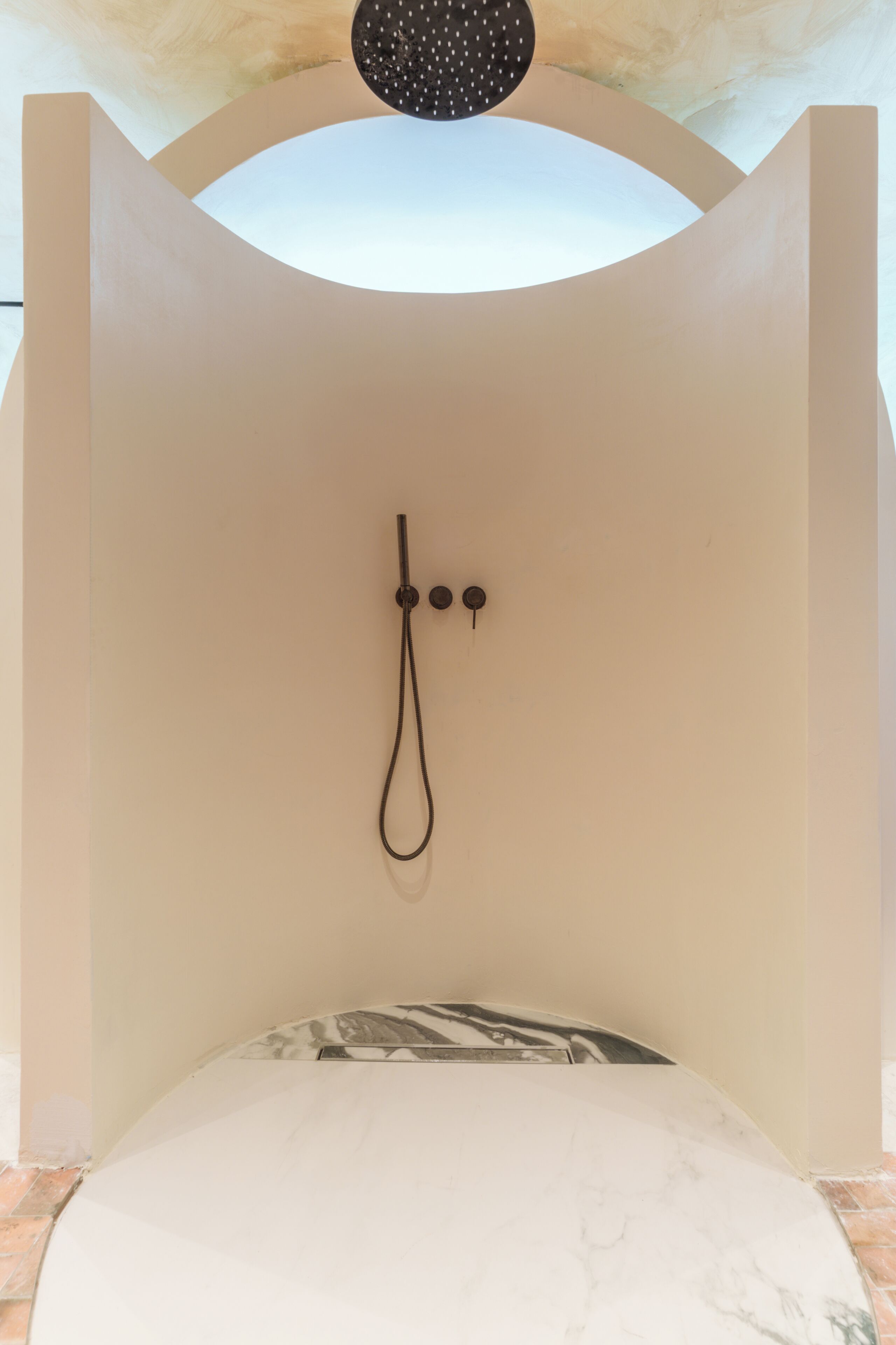 Habitación minimalista con cama individual, ducha y lámpara en el techo.