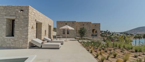 Un área de piscina con muros de piedra y sillas de descanso.