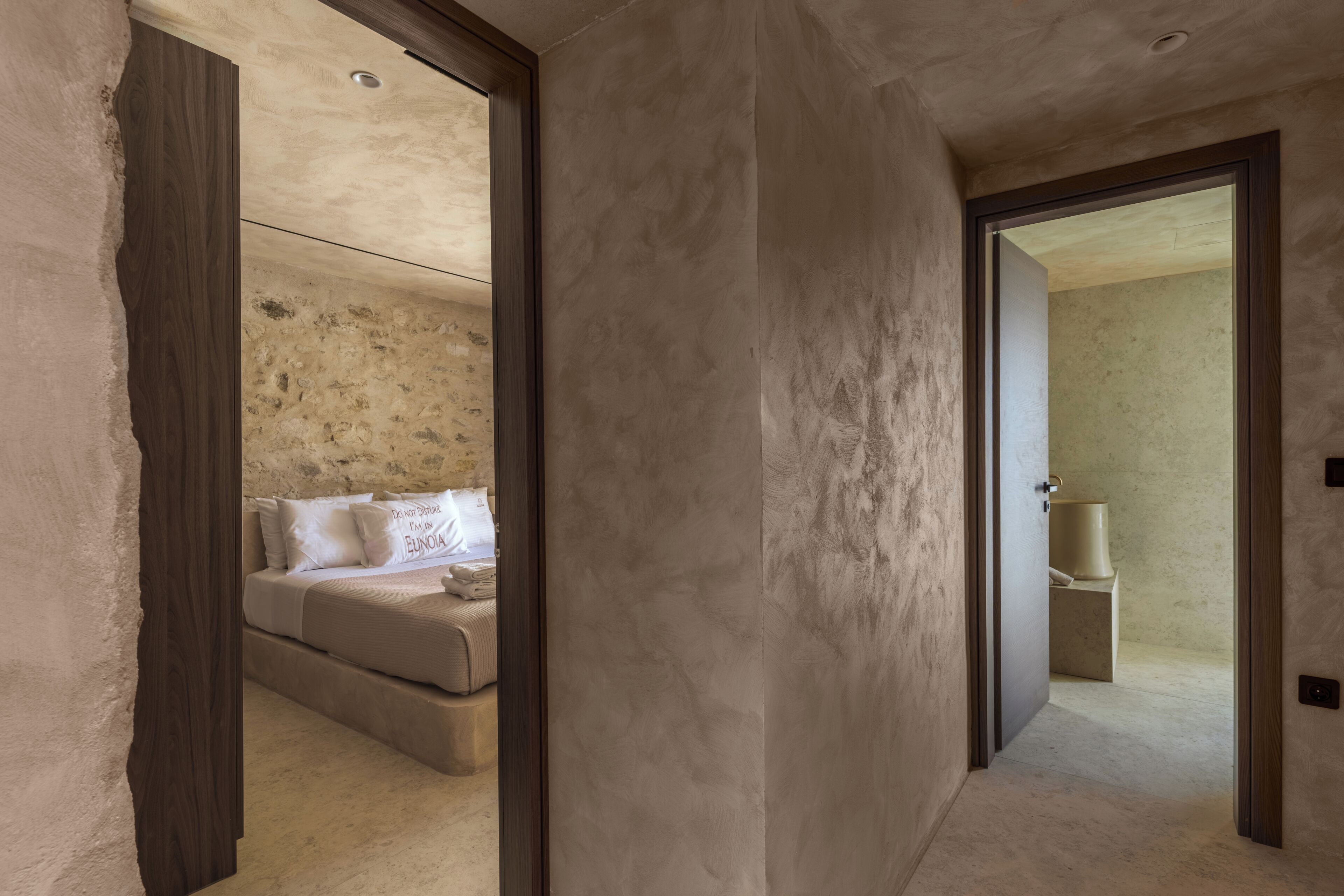 A hallway leading to a bedroom with a bed and a bathroom.