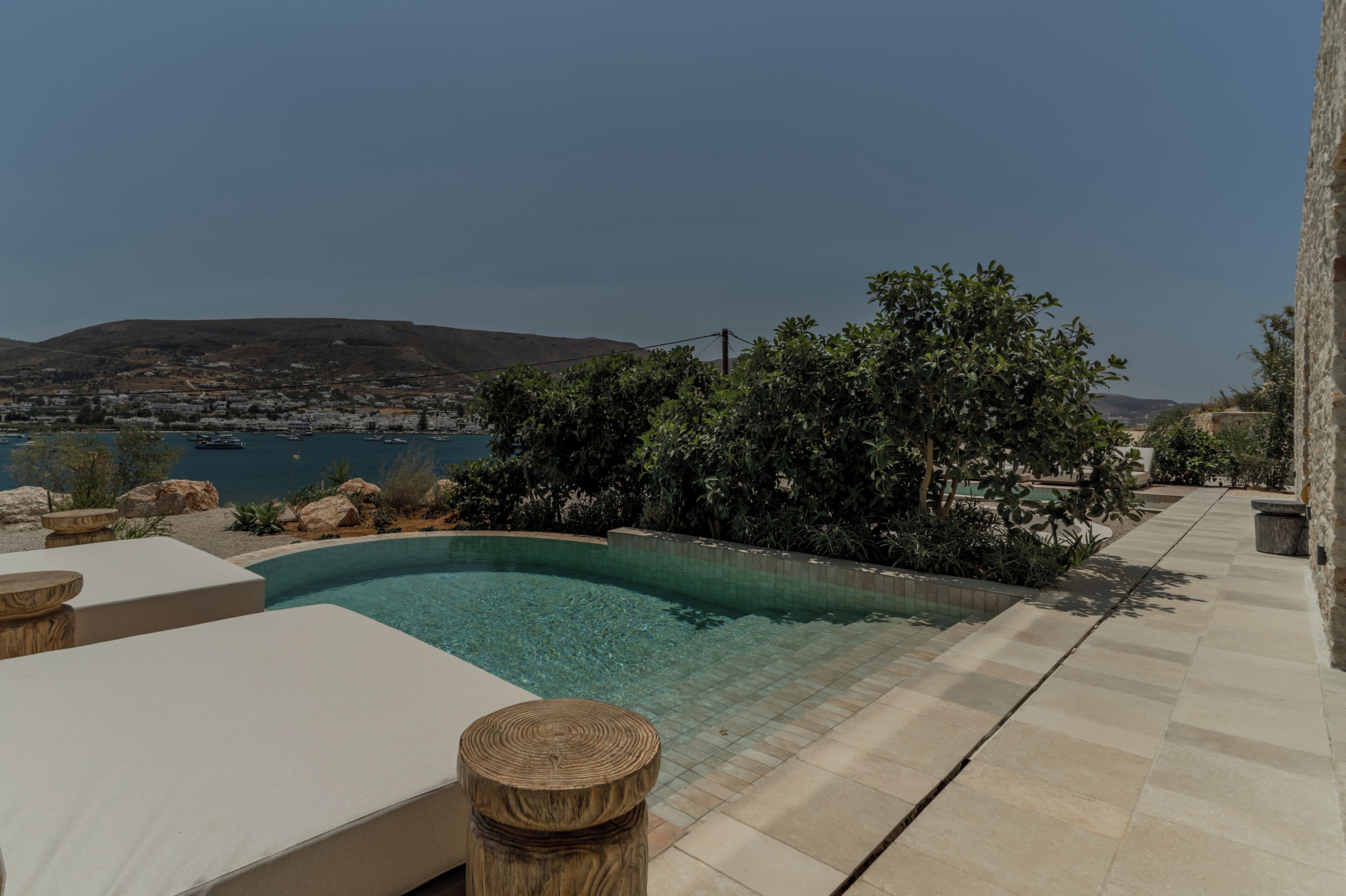 A swimming pool with a view of a coastal town and hills.