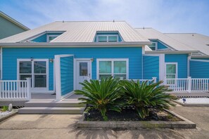 Ein zweistöckiges Haus mit blauer Fassade, weißer Verzierung und einer kleinen Veranda mit Geländer.