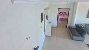 Un passadís amb una escala, un llit, un armari blanc i un sofà.
