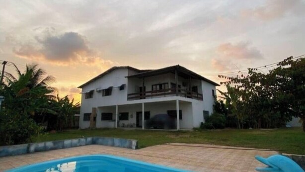 Una casa de dues plantes amb una piscina al primer pla.