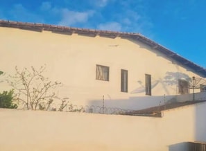 A building with a flat roof, three windows, and a barbed wire fence.