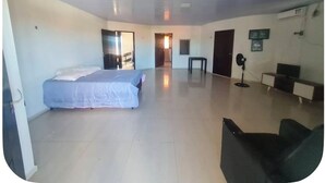 Una habitació àmplia amb un llit, un escriptori, una cadira i una televisió.