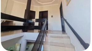 Una escala amb barana negra, parets blanques i un quadre encadrejat a la paret.
