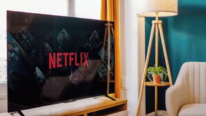 Une télévision ornée du logo Netflix, une lampe et une plante en pot dans une pièce aux murs de couleur turquoise.
