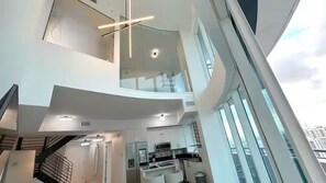Ein modernes Interieur mit Küche, Essbereich und einer Treppe, die auf einen Balkon führt.
