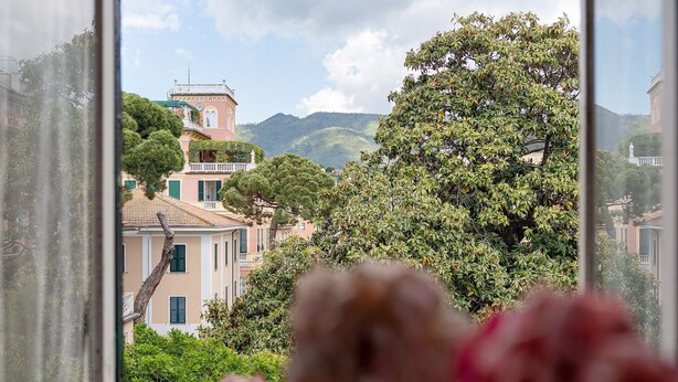 A view through a window of a building with a balcony, trees, and a mountain in the background. - Bed and Breakfast 'Sentieri' with Wi-Fi and Air Conditioning (Levanto)