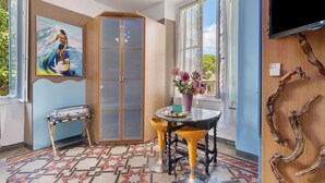 A room with a large window, a painting, a wooden cabinet, a table with chairs, and a patterned floor. - Bed and Breakfast 'Sentieri' with Wi-Fi and Air Conditioning (Levanto)