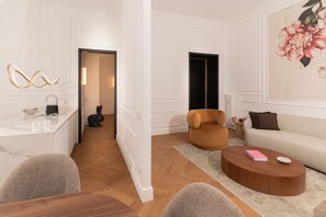 A modern living room with a sofa, a coffee table, and a chair. There is a kitchen area with a marble countertop and a sink. - Located on elegant Via Tacito in the prestigious Prati district, this stunning designer apartment offers a unique stay in the heart of Rome. Spacious and bright, it features three bedrooms, three refined bathrooms, a stylish living area and a modern kitc (roma)