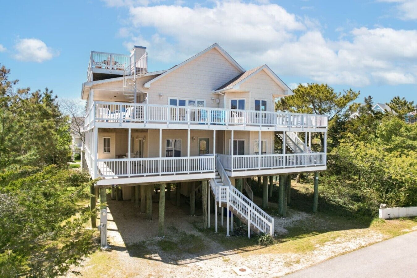 A two-story house with a balcony on the upper level, a staircase connecting the two floors, and a view of the surrounding trees.