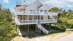 A two-story house with a balcony on the upper level, a staircase connecting the two floors, and a view of the surrounding trees. - Ocean View from Balconies | Steps to Private Beach (Rehoboth Beach)