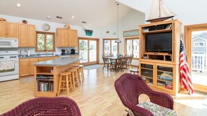 A spacious kitchen with wooden cabinets, a large island, and a dining area with chairs. - Ocean View from Balconies | Steps to Private Beach (Rehoboth Beach)