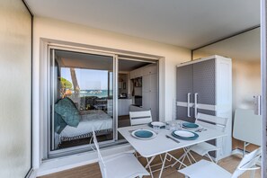 Varanda com mesa posta para dois, uma cama e vista para o mar.