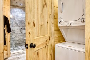 Ein Waschraum mit einer Holztür, einer Waschmaschine und einer Steinsäule im Hintergrund.